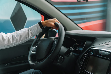 A man in classic clothes holds his hand on the steering wheel of a car. Rear view