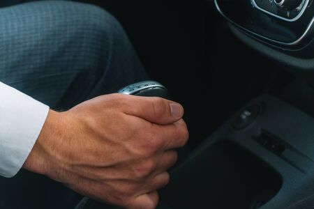 Man shifts gearbox in car. A man sits in a new car and switching gearbox leverの写真素材