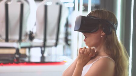 Amazed girl wearing virtual reality glasses. Virtual reality installation on the background. Expression of emotion of wonderの写真素材
