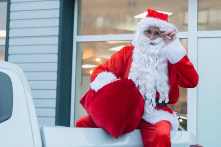 Santa Claus is sitting in the back of a pickup truck. Santa Claus at a car dealershipの写真素材