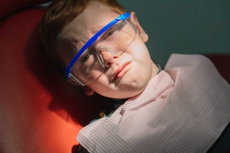 Scared red-haired boy crying at reception at dentist in dental chair. Pediatric dentistry