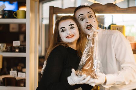 Happy man mime giving a chocolate eiffel tower to his girlfriend. Two happy mimes on a date in the cafeの写真素材