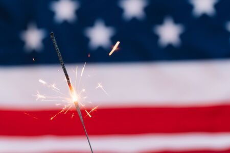 Sparkler with US flag in background. Celebrating of Independence Day or New Year and Christmasの写真素材