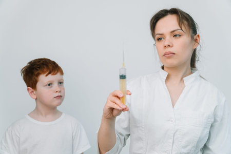 The doctor gives the child a flu shot. Close up of the kids arm and needleの写真素材