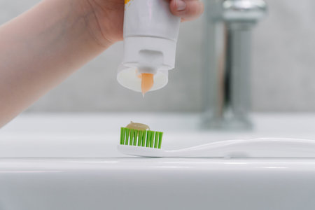 Child brushing teeth in the bathroom. Little boy puts toothpaste on a brushの写真素材