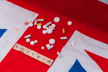 Mixed pills on UK flag with the inscription Britain. UK healthcare Planet and Britain quarantinedの写真素材
