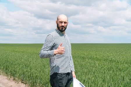 Portrait of young bearded farmer man with beard looking to camera in wheat fieldの写真素材