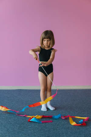Tender beautiful girl is engaged in gymnastics on a background of a pink wallの写真素材