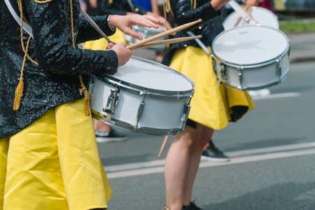 Close-up of hands of female drummers in yellow black vintage uniform at parade. Street performance. Parade of majorettesの写真素材
