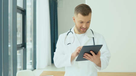 Young doctor studies the medical history in a tablet before the patient arrivesの写真素材