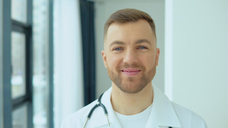 Successful physician in white lab coat looks at the camera and smiles in hospital officeの写真素材