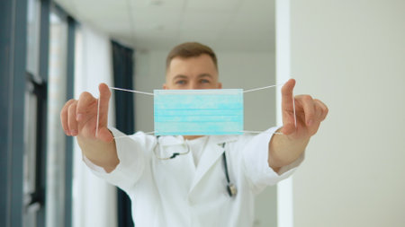 A male doctor holds a protective blue mask in front of him. Virus Protectionの写真素材