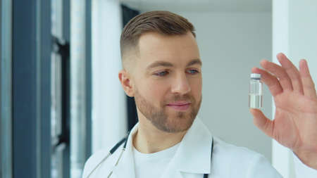 A doctor holds an ampoule with a vaccine in his hand.の写真素材
