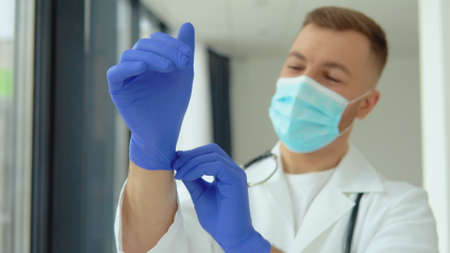 Young doctor in a protective mask puts on medical glovesの写真素材