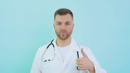 Doctor with stethoscope in white coat shows a sign of consent with his thumb up. Unbelievable promoの写真素材