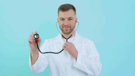 Male doctor with a stethoscope in a white coat on a blue backgroundの写真素材