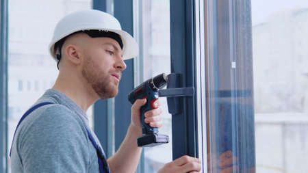 Master in a helmet and a screwdriver installs windowsの写真素材