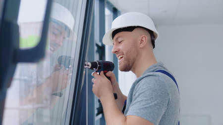 Window installer in a helmet and a screwdriver installs windowsの写真素材