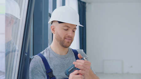 Window installer with a screwdriver stands near the windowの写真素材
