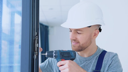 Master in a helmet and a screwdriver installs windowsの写真素材