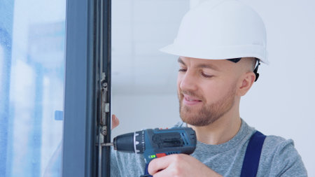 Window installer in a helmet and a screwdriver installs windowsの写真素材