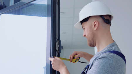 Window installer measures the dimensions of the window frame with a meter tapeの写真素材