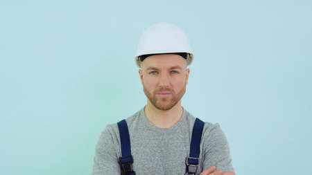 Serviceman in a helmett and overalls looking at camera on blue backgroundの写真素材