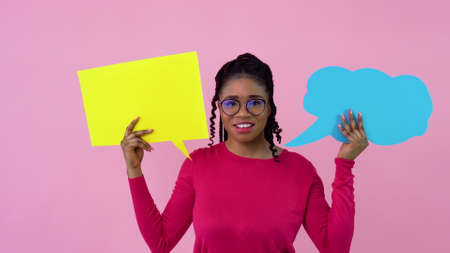 Cute young african american girl in pink clothes stands with posters for expression on a solid pink background. A place for advertising slogansの写真素材