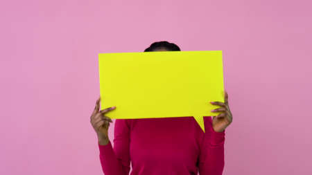Young african american girl stands with posters for expression on a solid pink background. A place for advertising slogansの写真素材