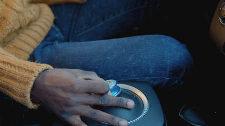 The dark-skinned driver switches the position of the lever in the electric car. Close-up view of handsの写真素材