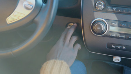 African american driver starts the electric car by pressing the button on the control panel