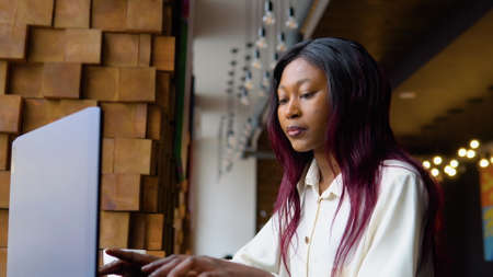 Young african american woman using laptop computer in cafe. Female professional working with notebookの写真素材