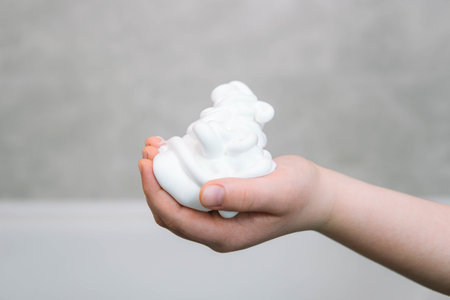 Shaving foam on a boys hand in the bathroom close up