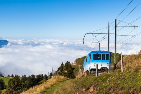 Lucerne, Switzerland - September 14, 2014 - The cogwheel train for tourists running toward the top of Rigi mountain. Famous tourists place near Lucerne, Switzerland. With magnificent cloud scape in the background.のeditorial素材