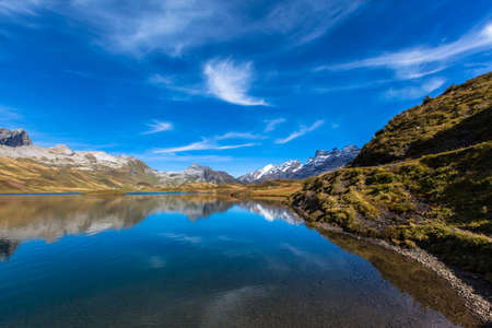 Stunning view of Tannensee with beautiful reflection of the Alps in the direction of Titlis, in central Switzerland, Canton of Obwalden.の写真素材