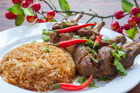 Close up view of grilled lamb chop served with rice, with spicy red chili, coriander, etcの写真素材