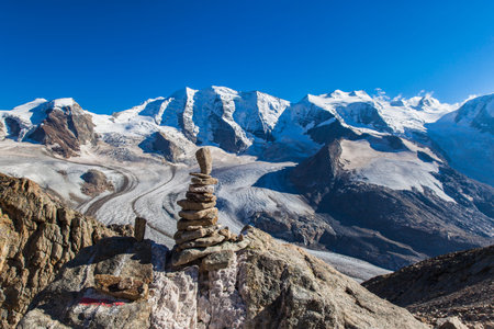 Stunning view stone heap at the top of Munt Pers with the Bernina massive including Piz Palu and...
