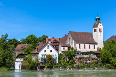Peaceful view of a small church on the riverside of Rhine on a sunny day, on the border between...
