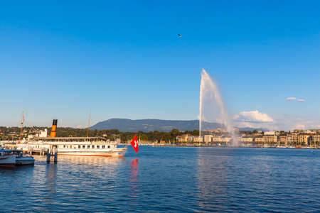 Beautiful view of the water jet fountain in the lake of Geneva and the cityscape of Geneva at sunset, Switzerlandのeditorial素材