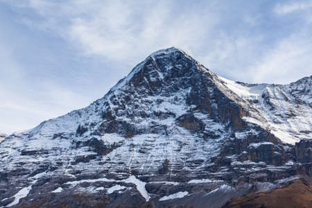 Stunning close up view of famous Eiger north face of Swiss Alps on Bernese Oberland with glacier and snow on cloudy autumn day, Canton of Bern, Switzerlandの写真素材