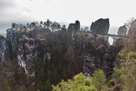 Panorama view of Bastei Bridge and sandstone mountains in Saxon Switzerland National Park on a foggy winter day, Saxony, Germanyの写真素材