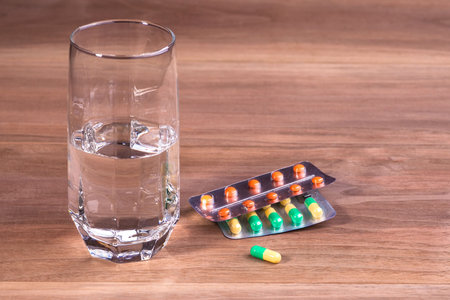 Tablets, a glass of pure water, a thermometer. On a white background.