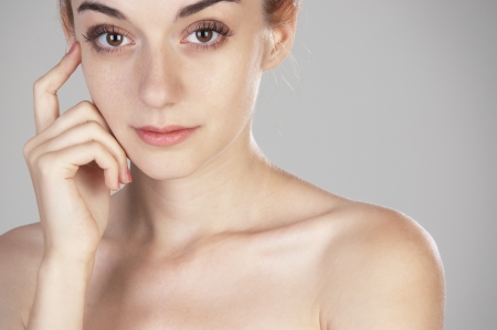 Portrait of beautiful girl of nineteen touching her hand to her face and looking at the camera close upの写真素材