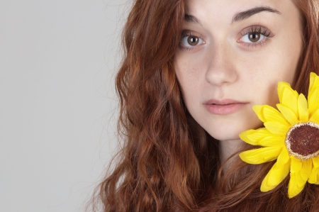 Portrait of a red haired girl of nineteen with yellow flower on her shoulderの写真素材
