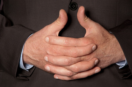 Man in suit clasped fingers in front of him closeupの写真素材