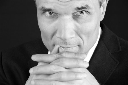 Grey-haired man in suit at the age of forty-six years old  with hands to head support on black...