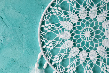 White dream catcher on turquoise textured background. Texture of concrete. の写真素材
