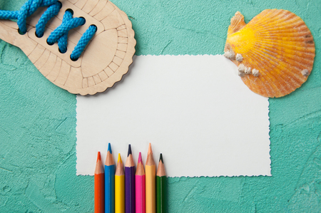 White blank note, pencils and orange shell on turquoise textured background.Top view and copy space for textの写真素材