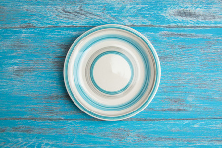Blue beige striped plate on blue wooden shabby background. Top view and copy space for textの写真素材