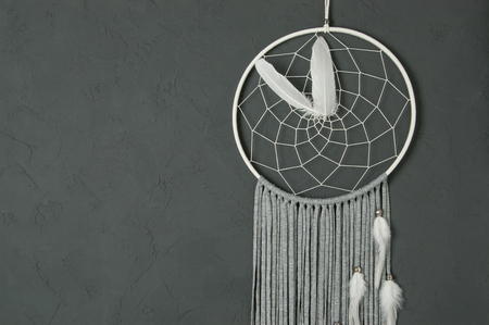 White gray dream catcher close up on dark gray textured background. Texture of concrete, copy space for textの写真素材
